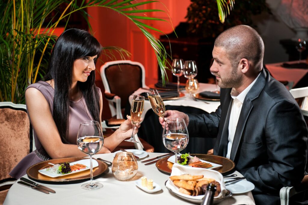 Beautiful couple with glasses of champagne at restaurant on romantic date